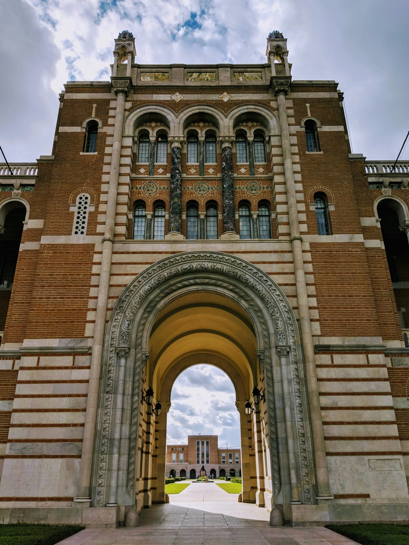 brown and white concrete arch building under dramatic clouds during daytime