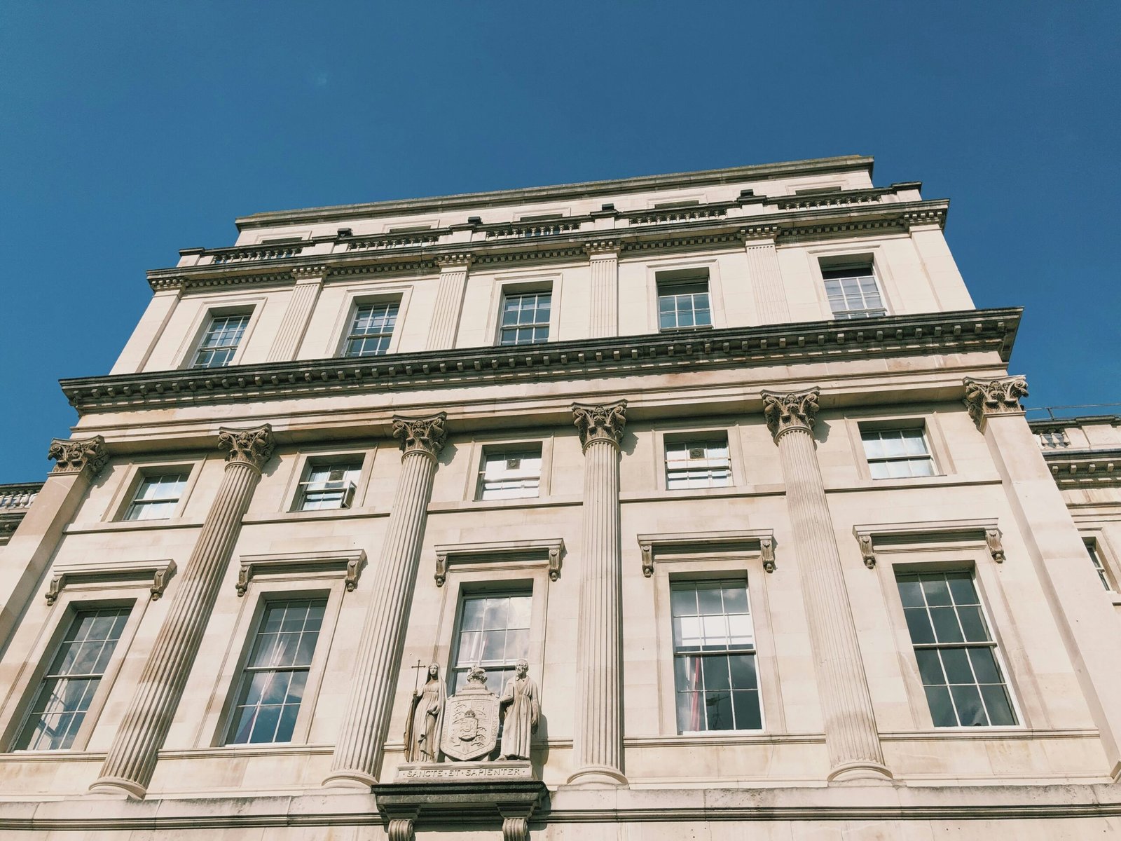 low-angle photography of white concrete multi-storey building under clear blue sky